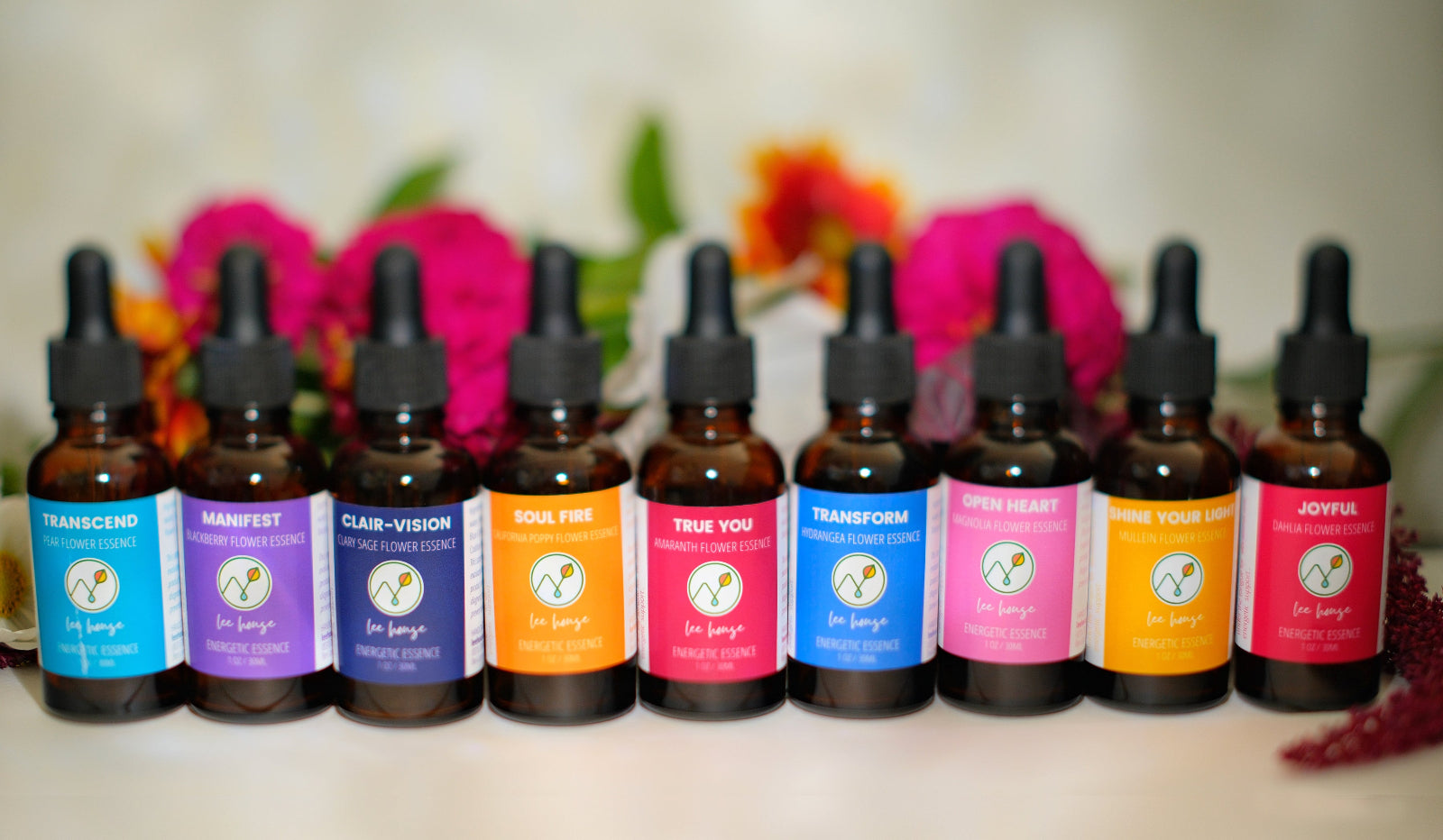 Row of colorful flower essence bottles with labels on a blurred floral background