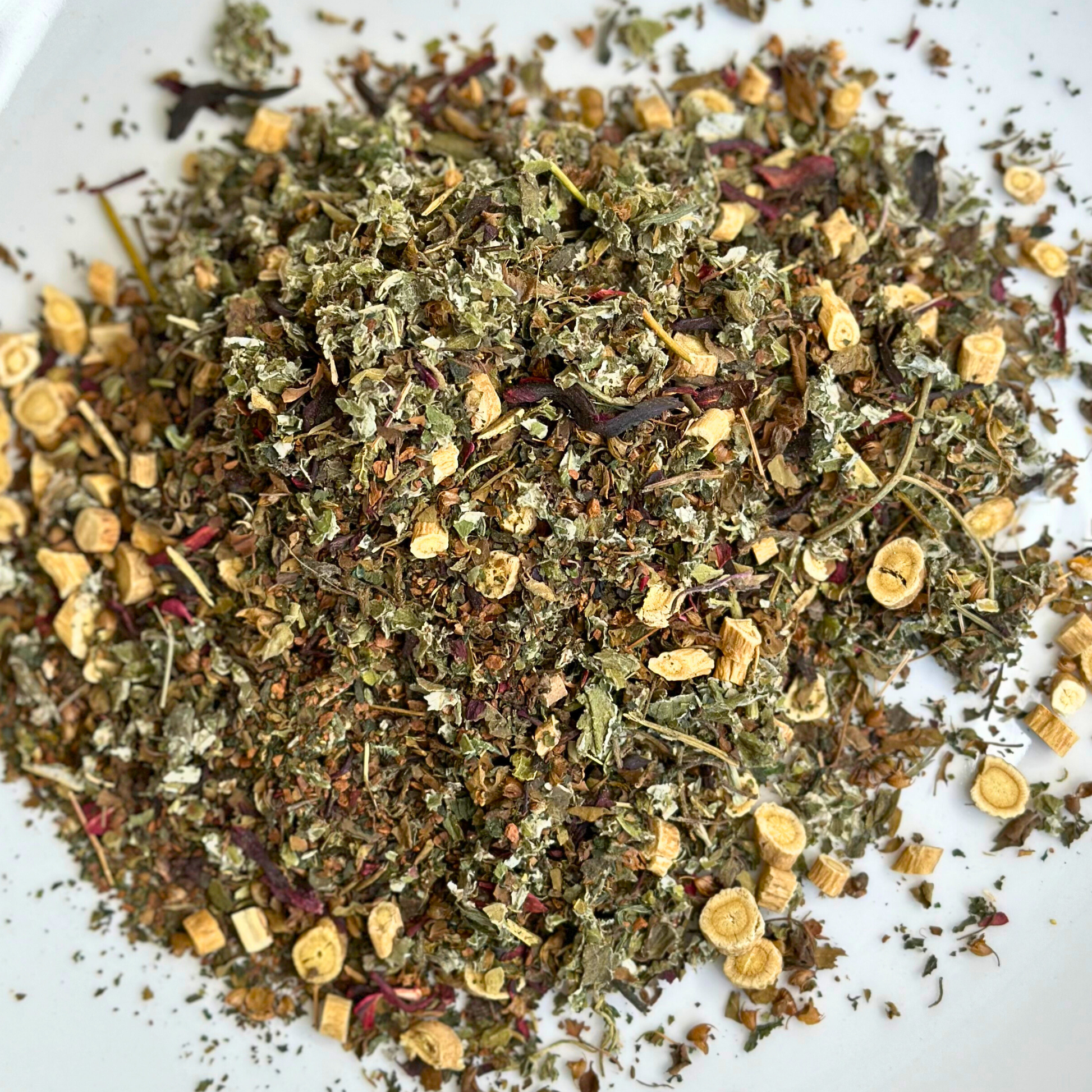 A mixture of dried herbs and spices, presumably the contents of Women's Balance Tea, displayed on a white background.
