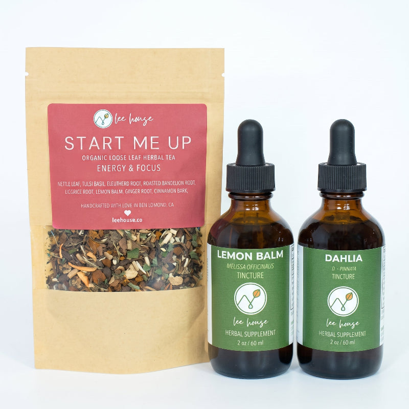 Lee House herbal supplement set including 'Start Me Up'  tea, and two amber glass dropper bottles labeled 'Lemon Balm' and 'Dahlia'.