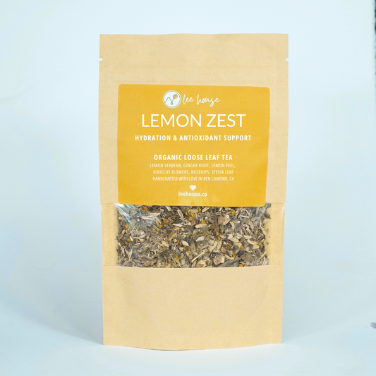 Bag of organic loose leaf tea labeled 'Lemon Zest' on a light blue background