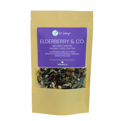 A stand-up kraft paper pouch of Lee Lows Elderberry & Co. wellness support organic loose leaf tea, featuring a prominent purple label and a clear window showing the loose leaf blend inside.