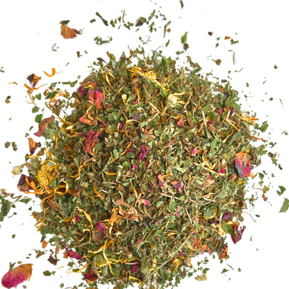 Close-up of Ease Herbal Tea in a bowl with vibrant dried rose petals, lemon balm, calendula, and peppermint leaves with a touch of purple from the gotu kola, creates a colorful and textured mosaic ofhand cut and blended herbs and blossoms.