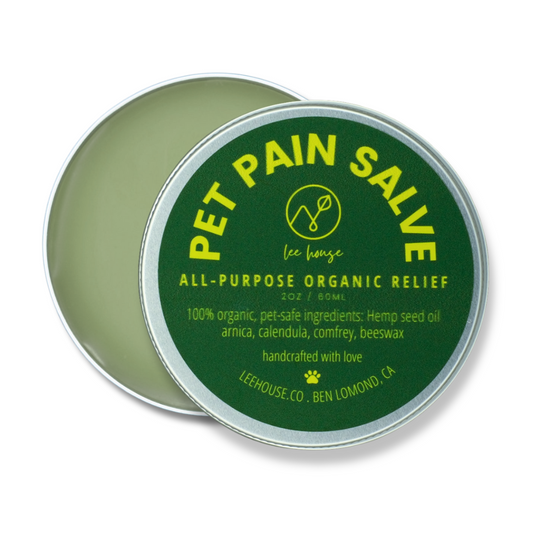 A small open tin container of Pet Pain Salve with the label detailing organic ingredients such as hemp seed oil, arnica, calendula, comfrey, and beeswax.