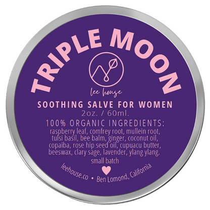 photo of a 2 oz tin of triple moon soothing balm for women depciting a purple and pin label that reads: 100% organic ingredients: raspberry Leaf, comfrey root, mullein root, tulsi basil, bee balm, ginger, coconut oil, copaiba, rose hip seed oil, cupuacu butter, beeswax, clary sage, lavender, ylang ylang. External Use Only. handcrafted with love, leehouse.co